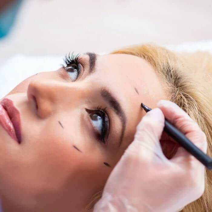Cosmetic surgeon drawing lines on patient for cosmetic surgery